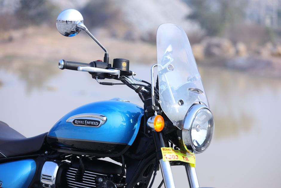 Close-up image of a black motorcycle parked on a paved roadside with a fairing windshield, rearview mirrors, and front headlight visible. The motorcycle features a UK license plate reading 'XJL 35 K 8206' and is situated next to a grassy area with green foliage and trees in the background. The scene appears to be outdoors during daylight, with natural lighting illuminating the motorcycle and surroundings. The image may be related to house removals or moving logistics, such as transport or packing procedures, and showcases the motorcycle as part of a larger move or transfer process, typical of home relocation services provided by Enfield Removals.